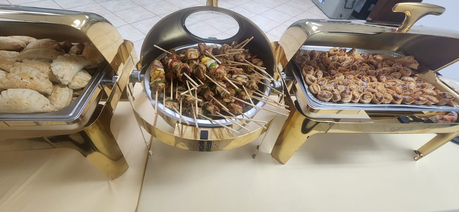A catered buffet with pastries and savory dishes in polished serving trays