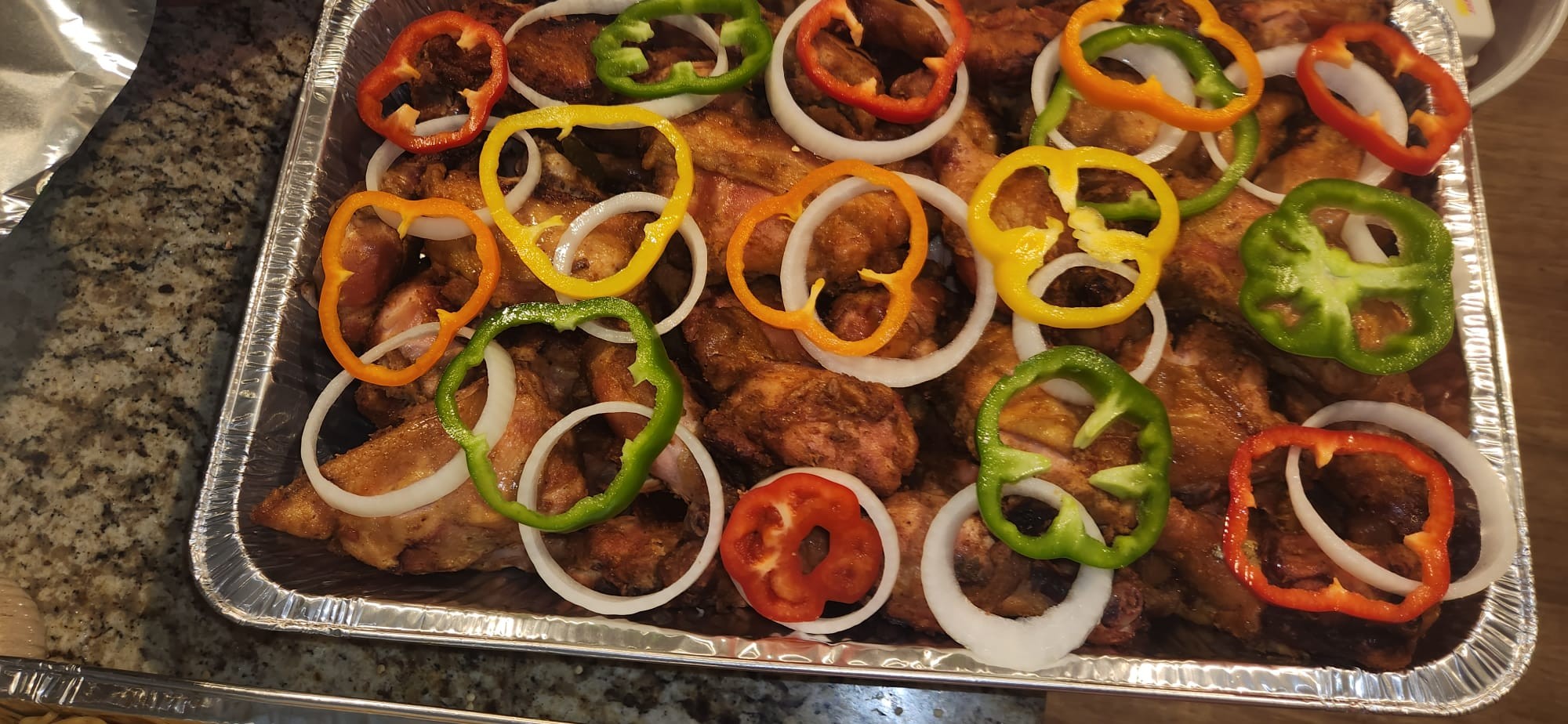 Grilled fish garnished with colorful peppers and onion rings